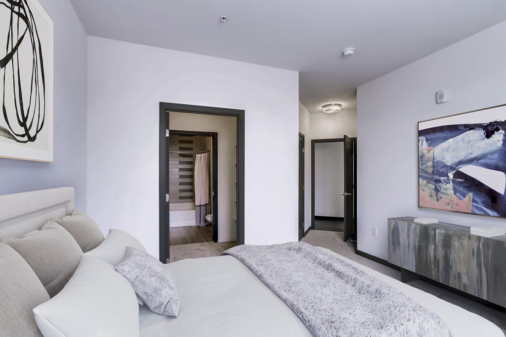 a white bedroom with a large bed and a door to a bathroom
